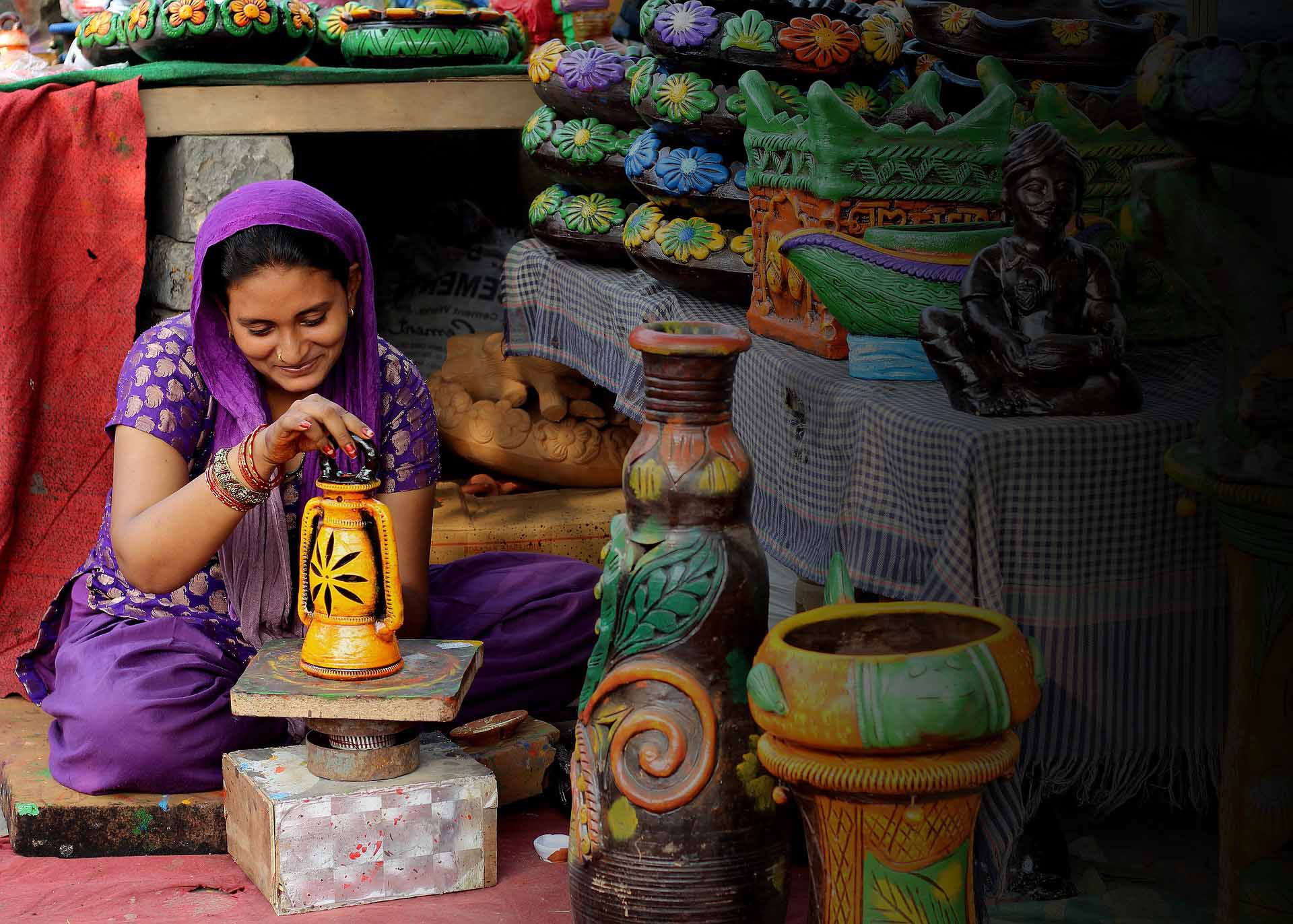 A woman crafting a clay pot under an NGO